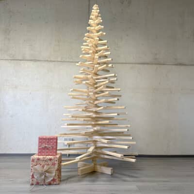 Xtra Franky Weihnachtsbaum (220 cm Höhe, 115 cm Durchmesser) in aufgedrehter Form aus Holz, umgeben von Geschenken.