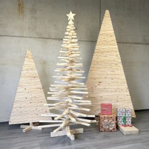 Nachhaltiger Holzweihnachtsbaum zum Zusammenstecken aus Holzlatten, umgeben von modernen Holz Tannenbäumen und Geschenken.