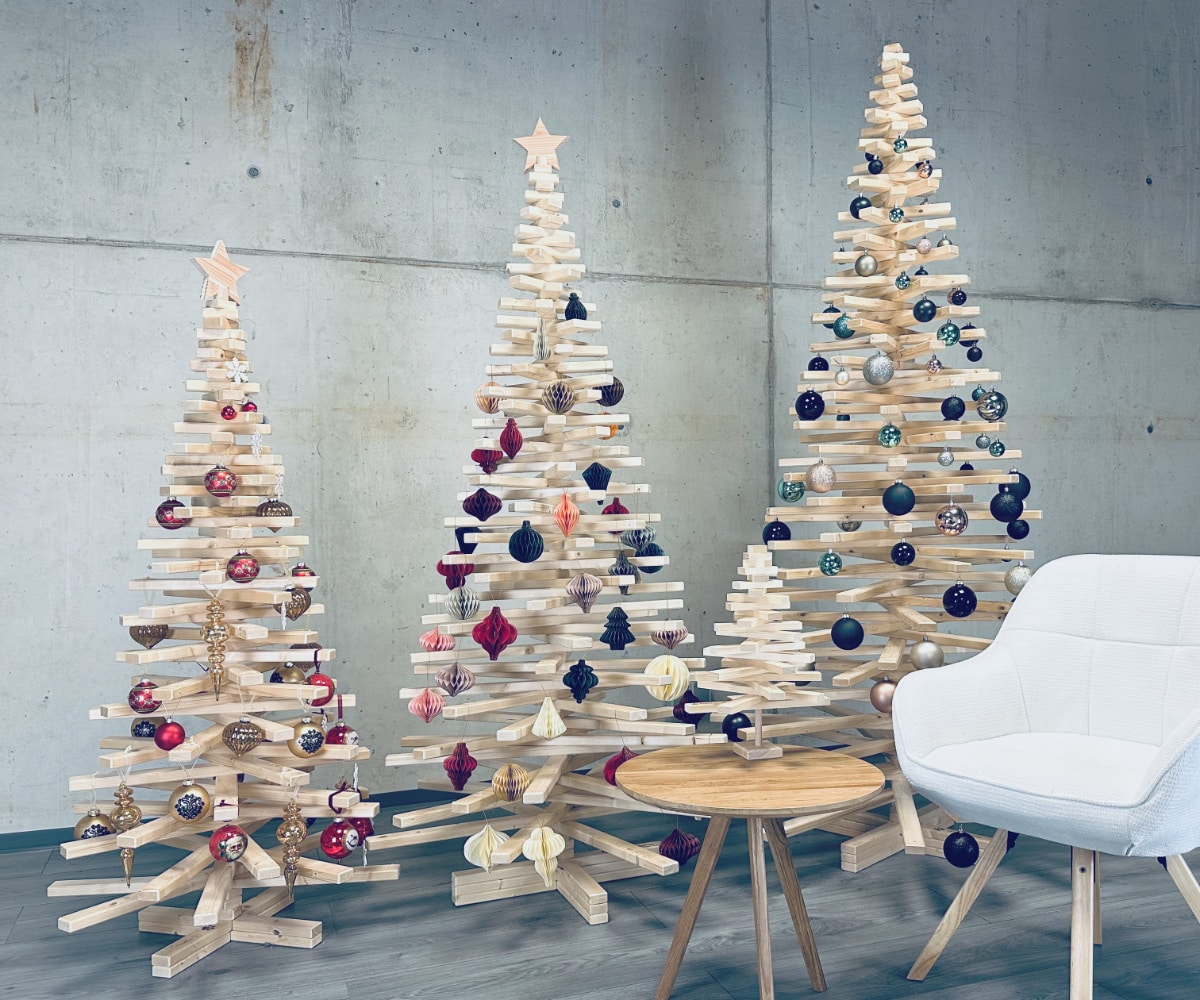 Franky Tree ist ein alternativer Weihnachtsbaum aus Holz. Auf dem Bild sind drei Holzweihnachtsbäume zu sehen in einem industriellen Setting mit Betonwänden und Geschenken vor den Bäumen